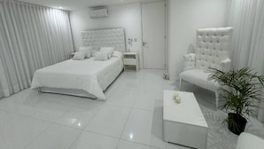 A modern bedroom with a large bed, a sitting area with a chair, and a small table. - Serena Boutique Potrero Garay (Alta Gracia)