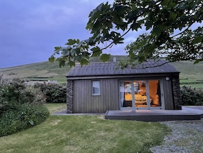 Een klein, rustiek vakantiehuisje met een stenen fundering, grote ramen en een veranda.