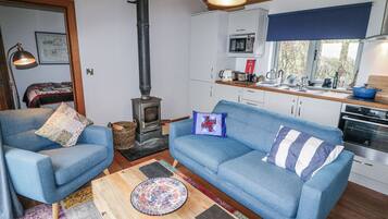 A cozy living room with a blue sofa, a wooden coffee table, and a wood-burning stove.