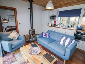 Een gezellige woonkamer met een blauwe bank, een houten salontafel en een houtkachel.