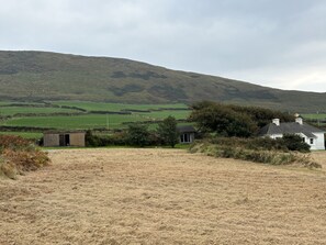 A rural landscape with a white house, a small shed, and a hill in the background. - BOSCA NEADU, romantic, with open fire in Dingle, County Kerry (Dingle)