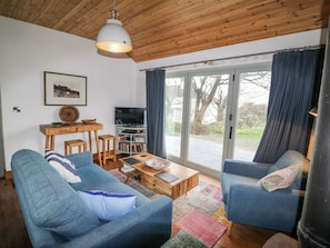 A modern living room with two blue sofas, a wooden coffee table, a TV on a stand, and a large window with curtains. - BOSCA NEADU, romantic, with open fire in Dingle, County Kerry (Dingle)