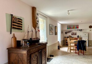 Een keuken met een houten tafel, stoelen, een koelkast en diverse keukengerei dat aan de muur hangt.