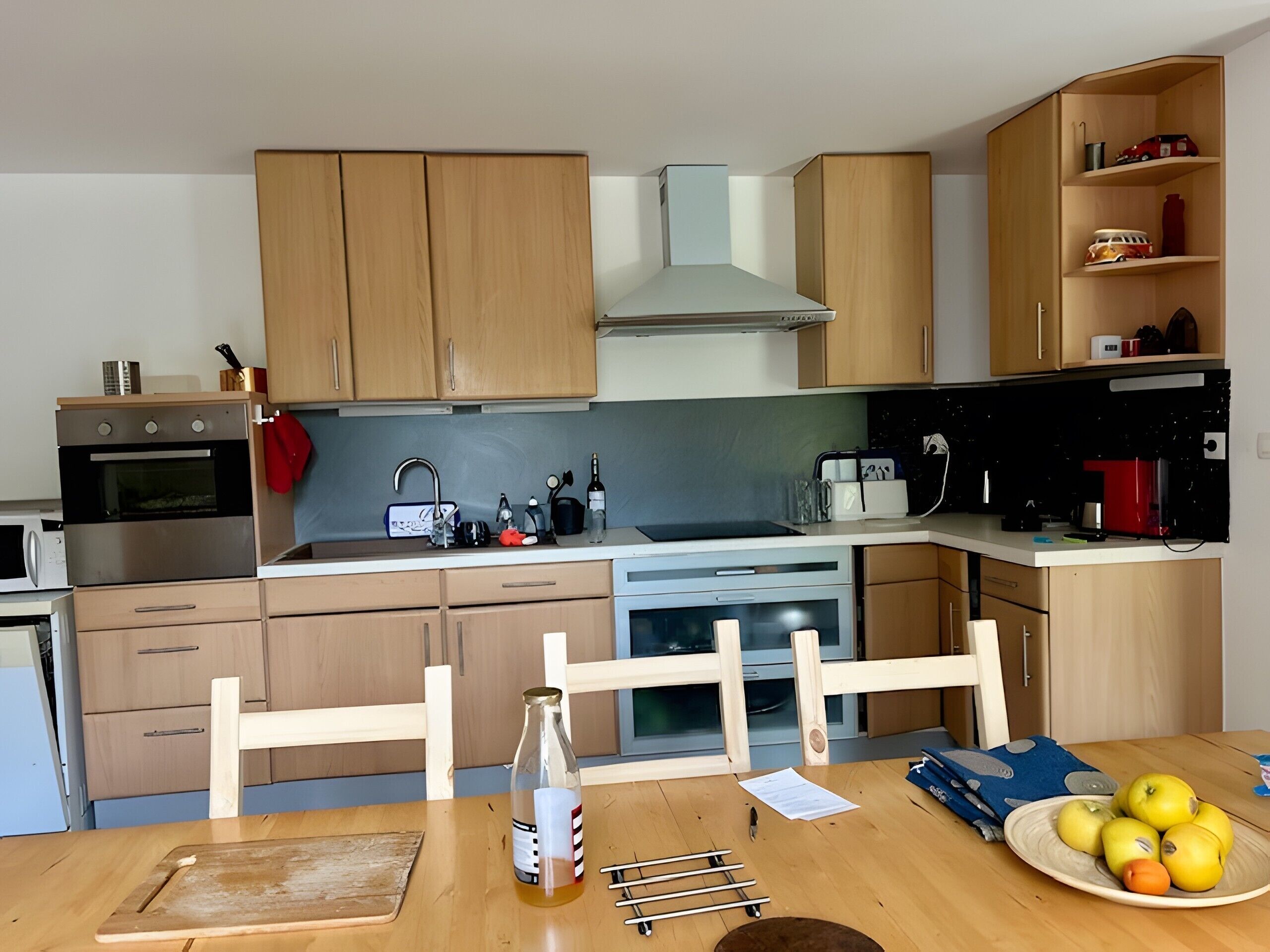 A kitchen with wooden cabinets, a microwave, a stove, a sink, and a dining table with chairs.