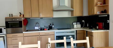 A kitchen with wooden cabinets, a microwave, a stove, a sink, and a dining table with chairs.