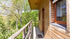Eine Holzhütte mit einem Balkon mit Blick auf einen bewaldeten Bereich.