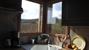 Eine Küche mit Spüle, Kaffeemaschine und Fenster mit Blick auf ein Feld.