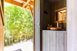 A wooden interior with a window opening to a bamboo garden. - Treehouse “La Cabane Perchée” (Vert)