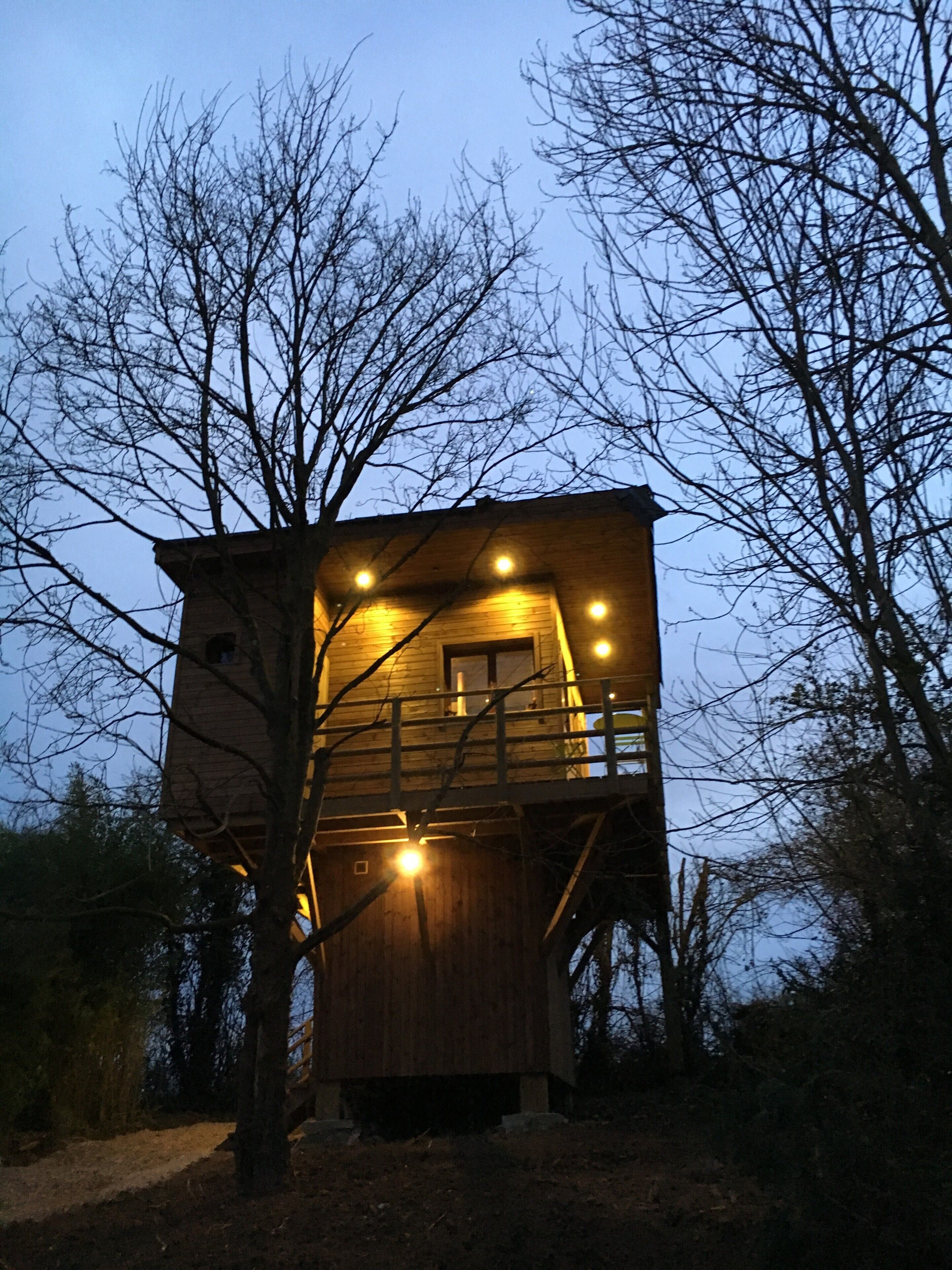 A wooden cabin with a balcony, surrounded by trees.