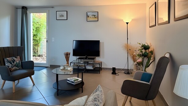 Un salon moderne avec un téléviseur à écran plat, deux canapés, une table basse et un lampadaire.