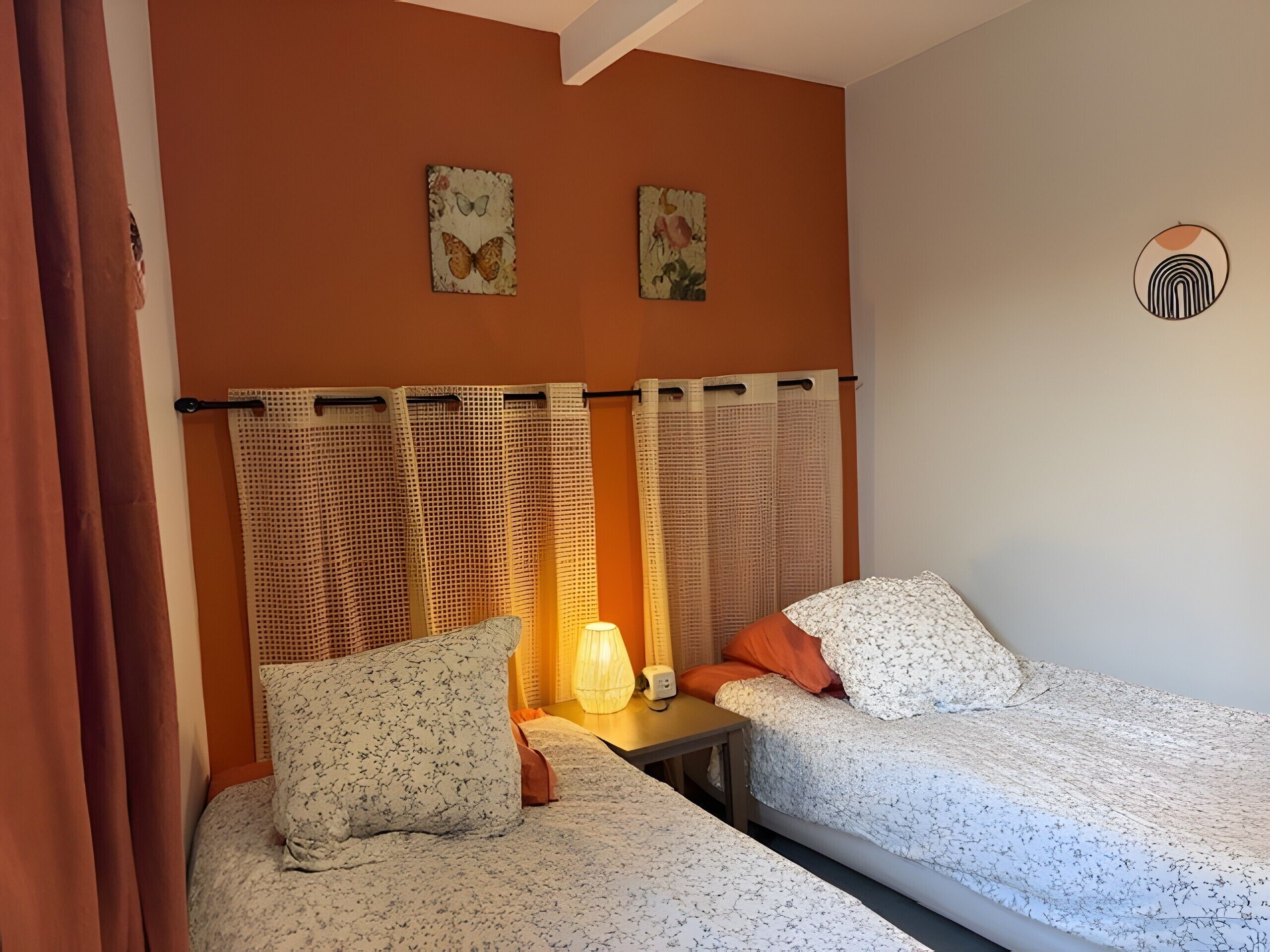 Ein Schlafzimmer mit zwei Betten, einem Nachttisch, einer Lampe und zwei Wandbildern.
