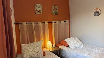 Ein Schlafzimmer mit zwei Betten, einem Nachttisch, einer Lampe und zwei Wandbildern.
