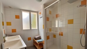 Une salle de bain avec une douche, un lavabo et une fenêtre.