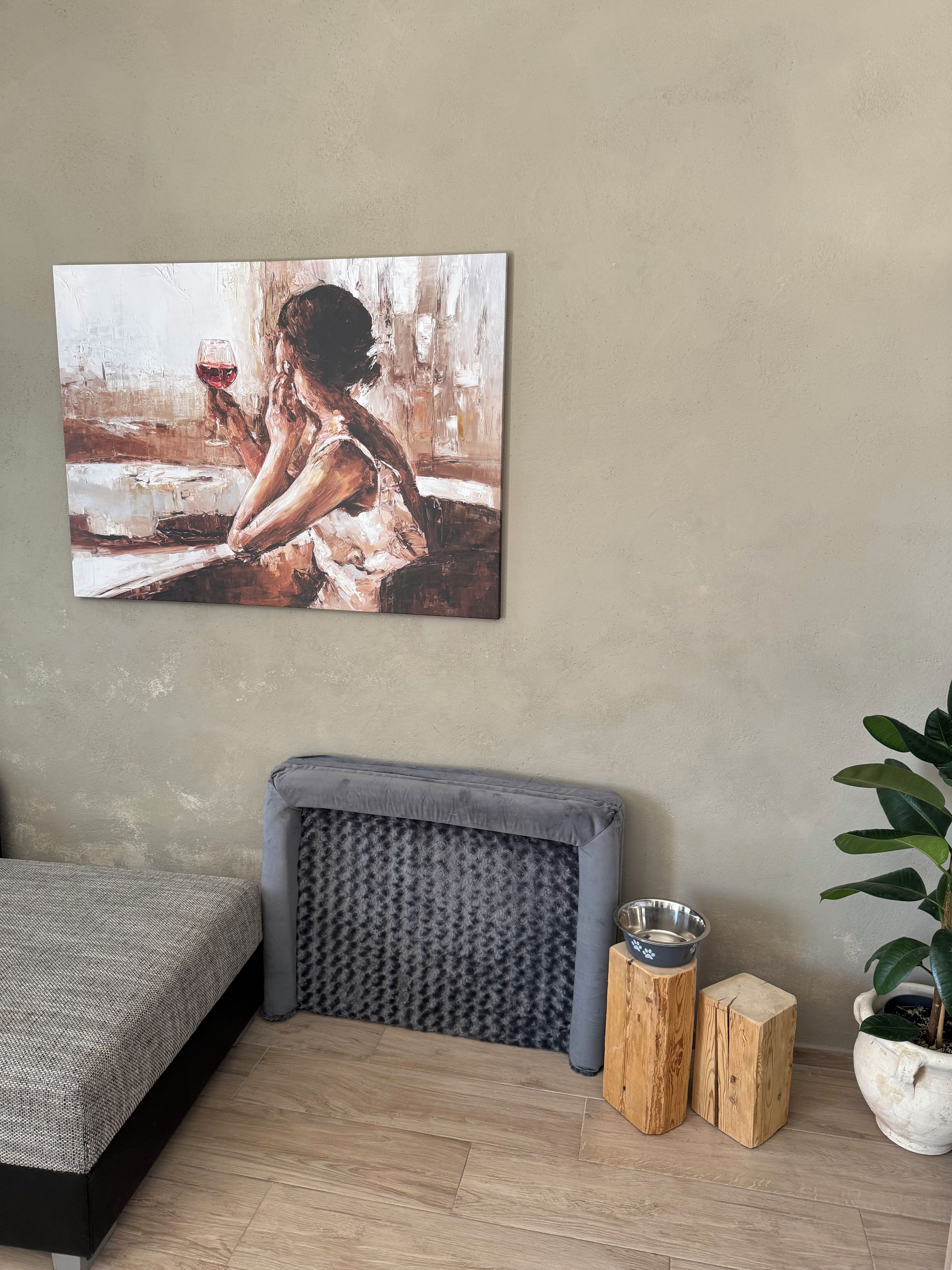 Una habitación con una cama, un banco, una planta en maceta y un cuadro en la pared.