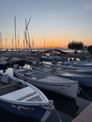 A marina with multiple boats docked, a bridge, and a tree in the background. - Villetta Moscal- Buon Gusto (Affi)