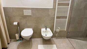 A bathroom with a toilet, bidet, towel, and a towel rack.