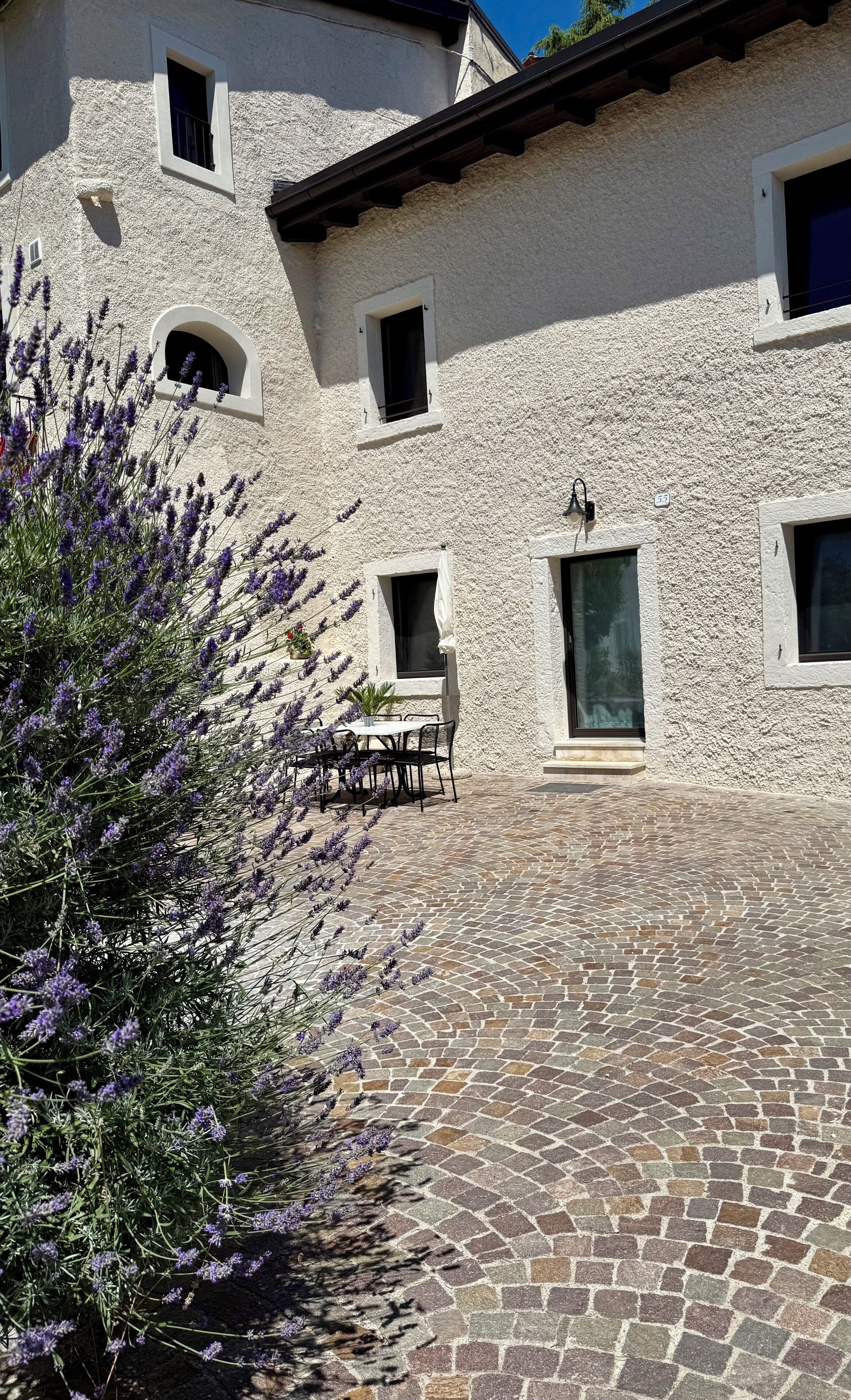 A building with a stone facade, multiple windows, and a paved courtyard.