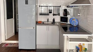 Une cuisine compacte équipée d’un réfrigérateur, d’un four à micro-ondes, d’un évier et d’un petit plan de travail sur lequel se trouvent une bouilloire et une machine à café.