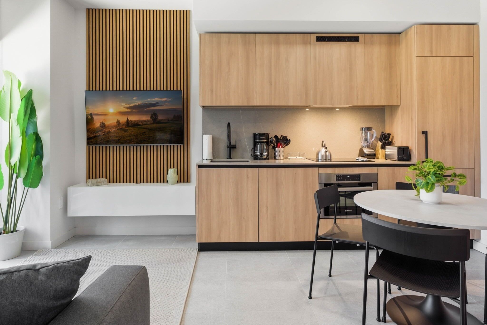Eine moderne Küche mit Holzschränken, einer integrierten Bank und einem Essbereich mit rundem Tisch und Stühlen.