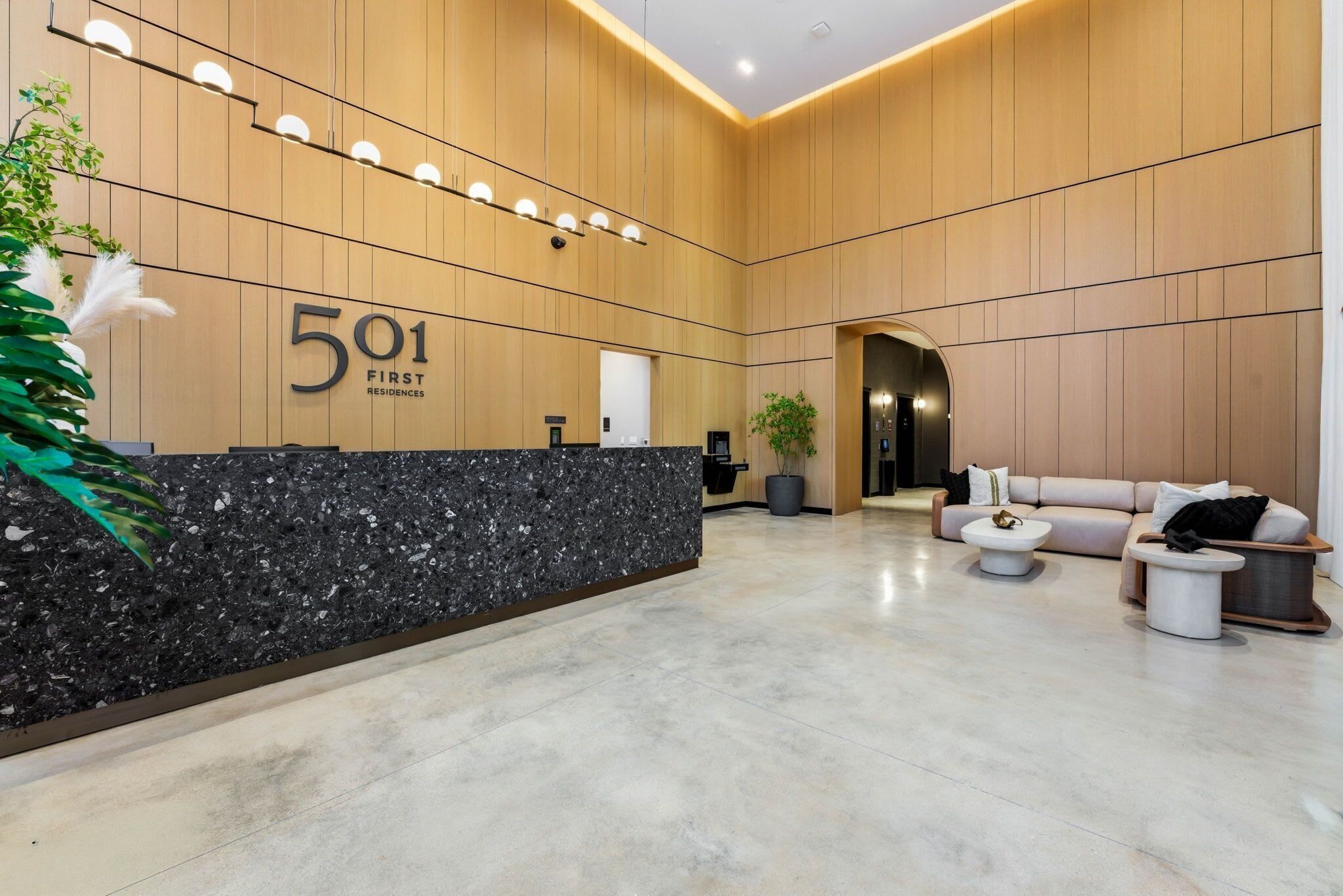 A modern reception area with a marble counter, a sofa, and a potted plant.
