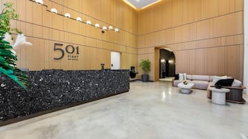 A modern reception area with a marble counter, a sofa, and a potted plant.