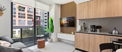 A modern kitchen with wooden cabinets, a built-in oven, and a large window overlooking a cityscape.