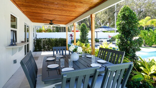 A covered outdoor dining area with a pool in the background. - Turfside Terrace, Heated Pool and Putt Putt (Jupiter)