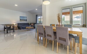 A modern living room with a sofa, a dining table with chairs, and a foosball table. - Lotus Elite Villa with Pool & Jacuzzi 7 (Pula)