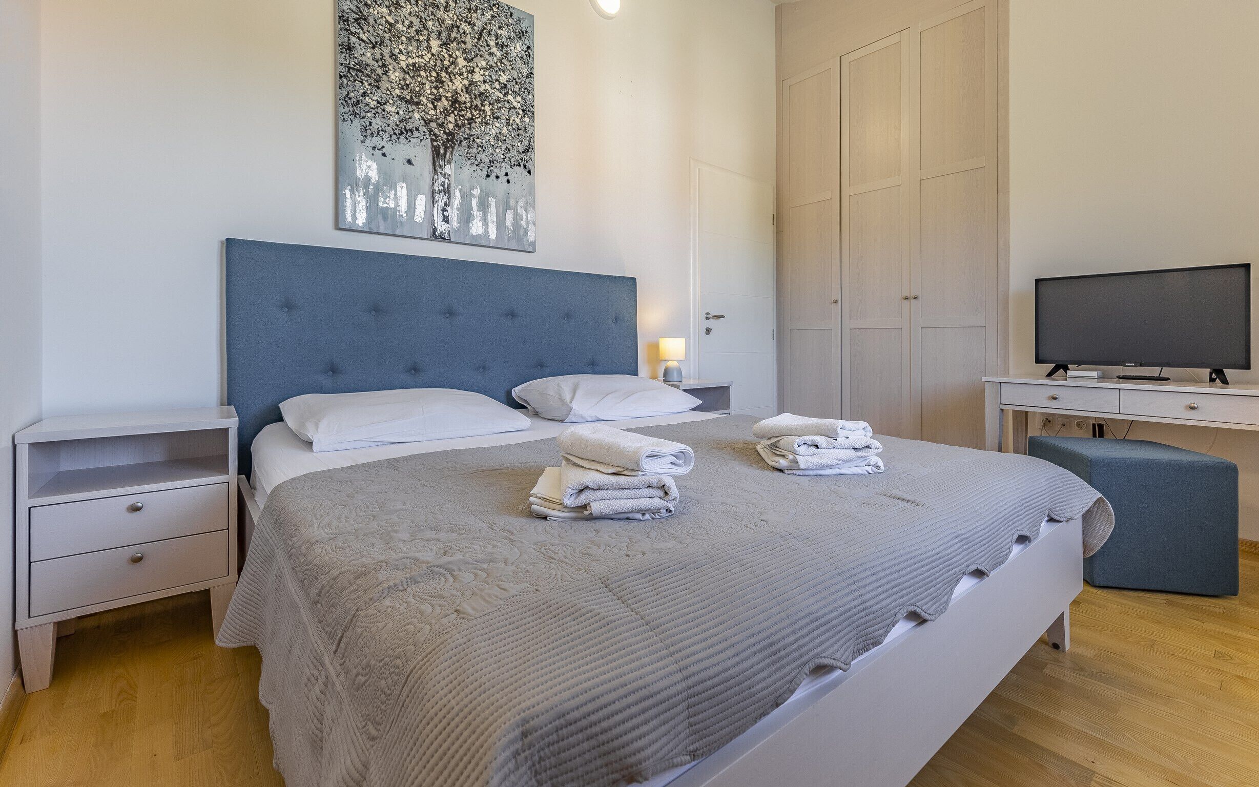 Habitación de hotel ordenada con cama, mesitas de noche, televisor y armario.