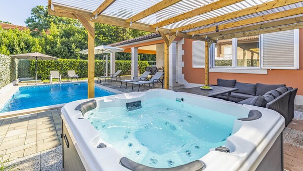 Zona de hidromasaje y piscina con sillas de descanso y sombrillas.