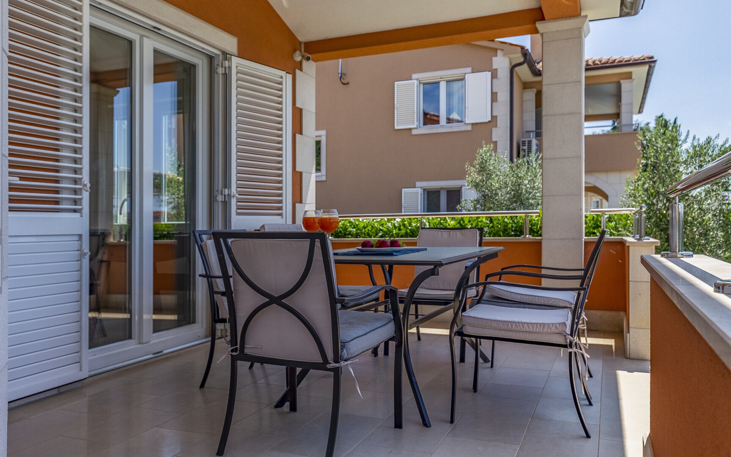 A balcony with a table and chairs, a sliding glass door, and a view of neighboring buildings.