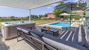 Un área de piscina en la azotea con hidromasaje, sillas de descanso y una sombrilla.