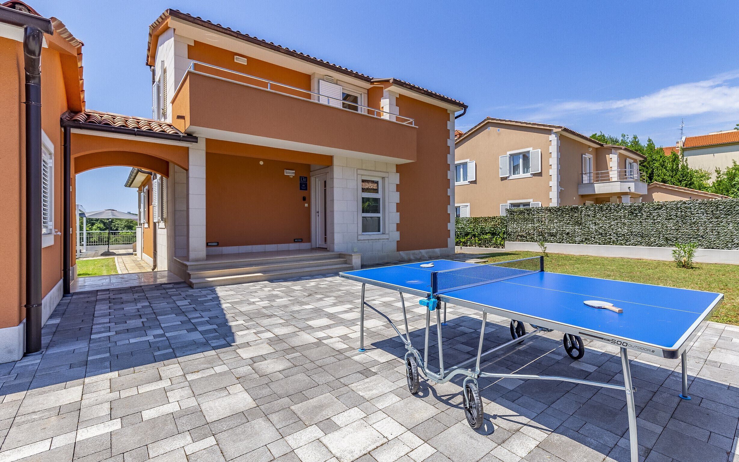 An outdoor ping pong table in a courtyard with a building in the background.