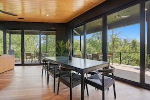 A modern dining area with a large table, chairs, and a view of the outdoors.