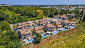 A residential area with multiple houses featuring tiled roofs, outdoor swimming pools, and lush greenery. - Lotus Elite Villa with Pool & Jacuzzi 3 (Pula)