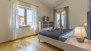 A bedroom with a bed, a bedside table with a lamp, a TV on a stand, and a wardrobe. - Lotus Elite Villa with Pool & Jacuzzi 3 (Pula)