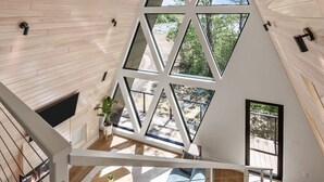 Un intérieur moderne avec un plafond en pente, une fenêtre au design géométrique et un escalier menant à un niveau supérieur.