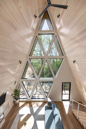 A modern interior with a triangular window design, wooden floors, and a ceiling fan.