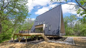 Une maison moderne avec un toit en pente, une terrasse et un escalier menant  à l’entrée.
