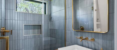 Un baño moderno con un espejo grande, un lavabo blanco y una zona de ducha.