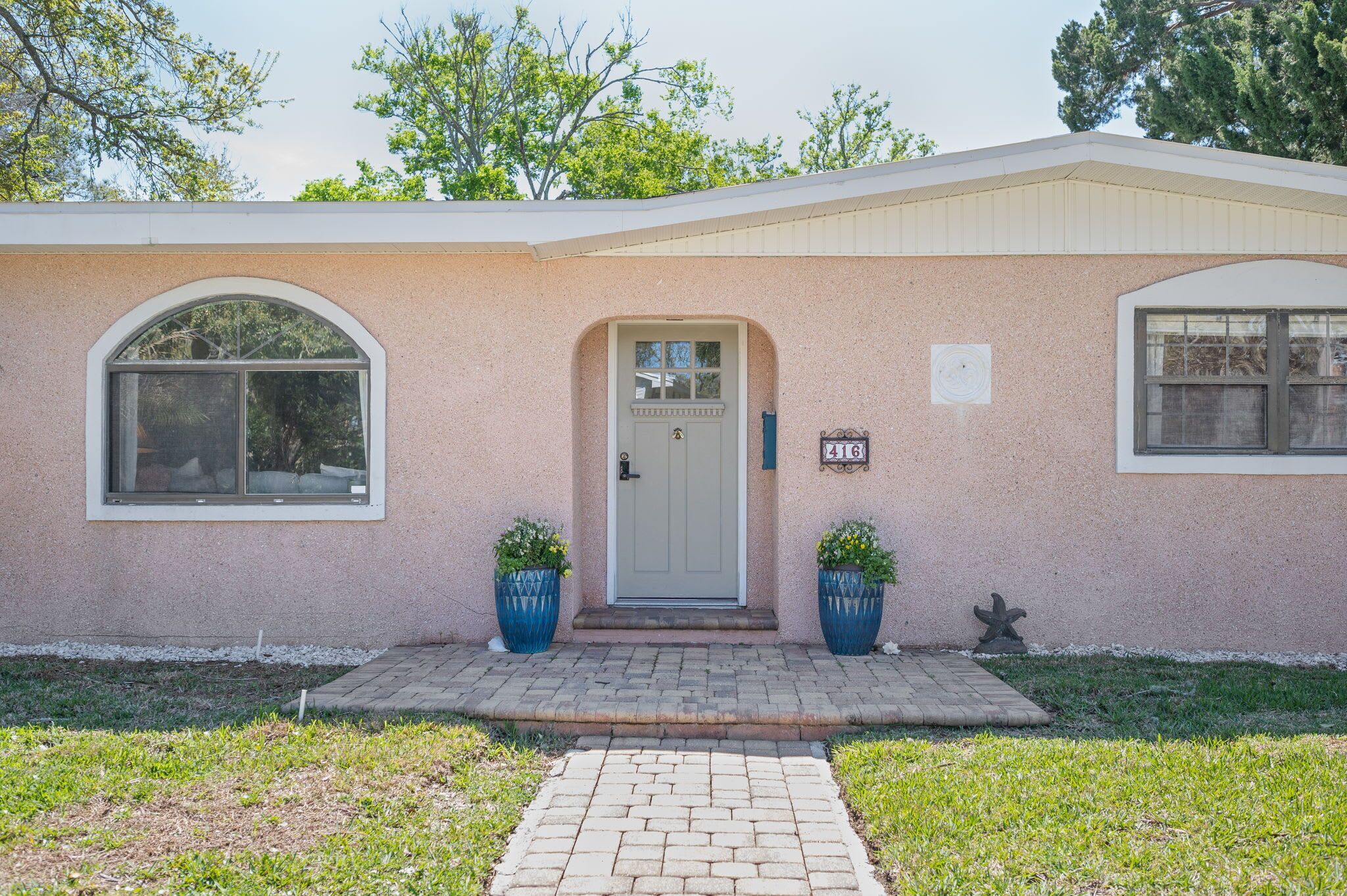 A single-story house with a front door, two large windows, and a mailbox.