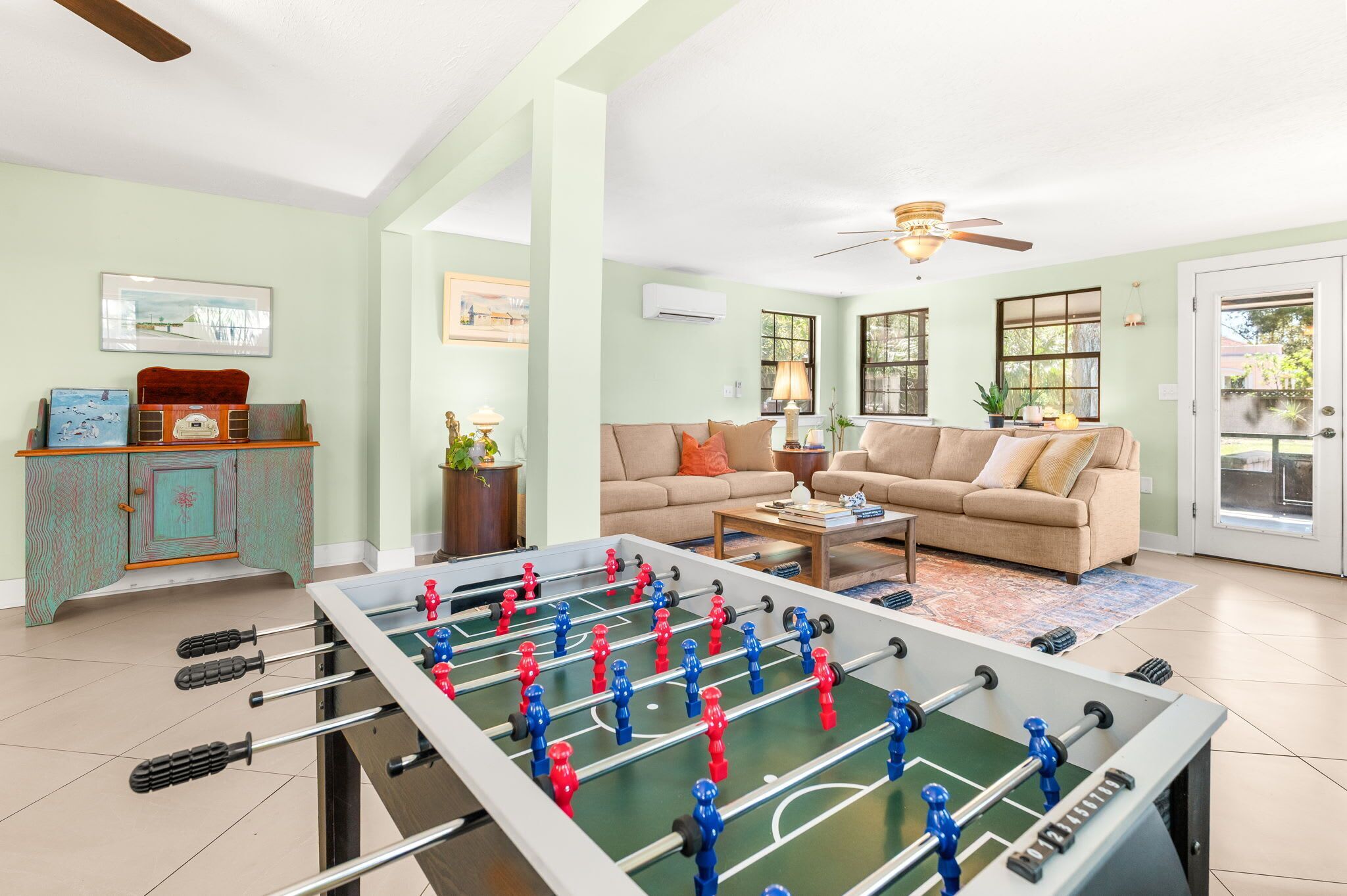 Una sala de estar con una mesa de fútbol de mesa, un sofá, una mesa de centro y un armario.