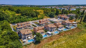 Zona residencial con varias casas de techo de tejas, piscinas al aire libre y abundante vegetación.