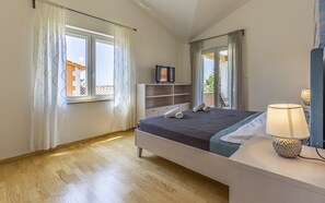Ein Schlafzimmer mit einem Bett, einem Nachttisch mit Lampe, einem Fernseher auf einem Schrank und einem Kleiderschrank.