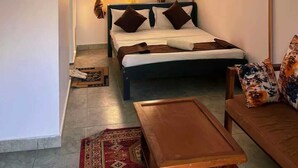 Ein Schlafzimmer mit einem Bett, einem Holztisch, einer Couch und einem dekorativen Baldachin.