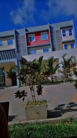 Un bâtiment moderne doté de nombreux balcons et d’une cour intérieure agrémentée de plantes tropicales.