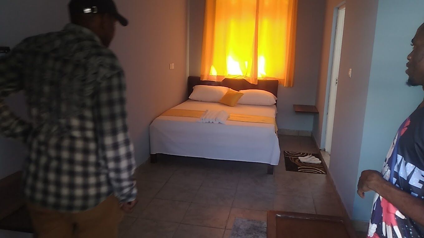 A hotel room with a bed, a nightstand, and a window with curtains.