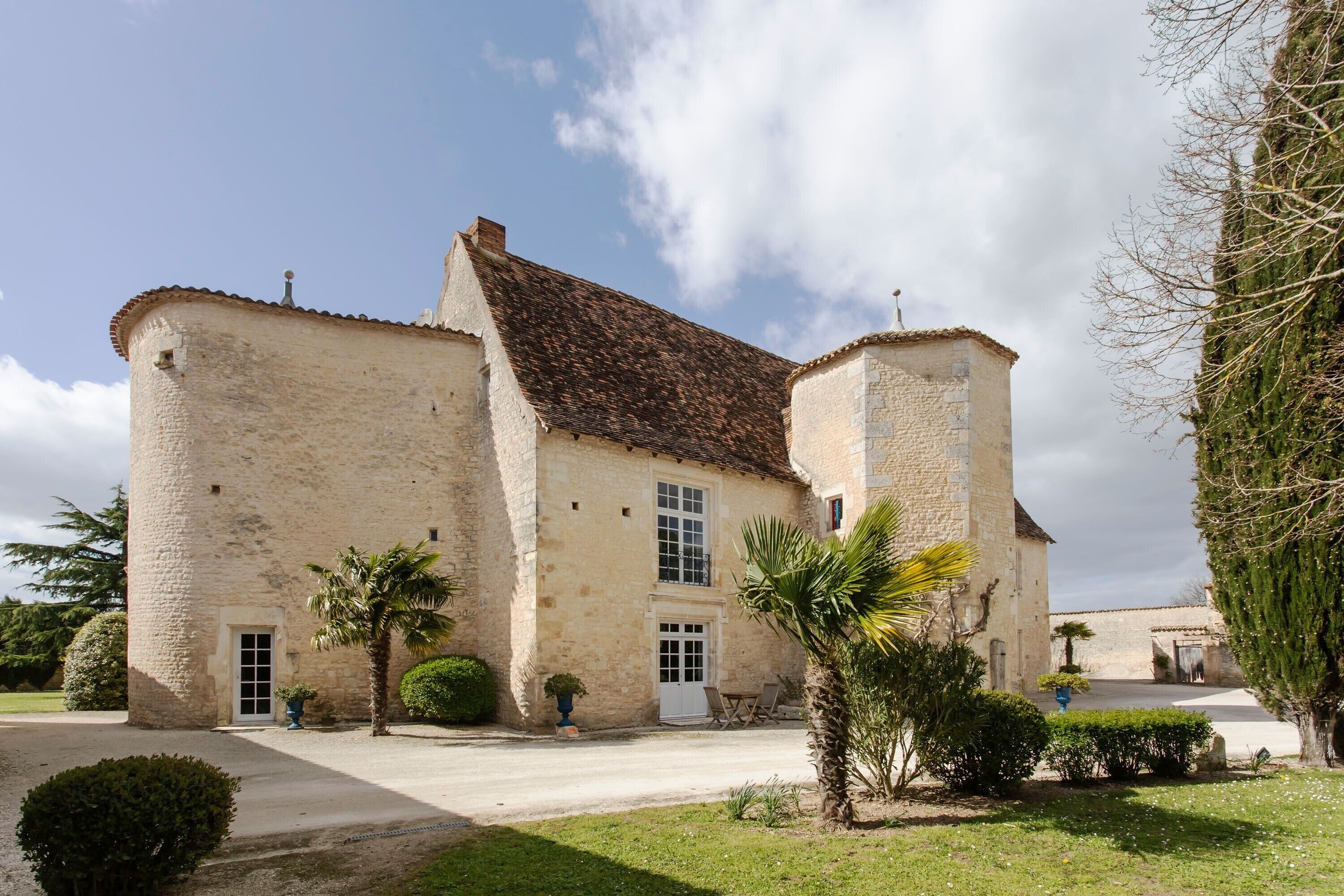 A stone building with a courtyard, a palm tree, and a small garden.