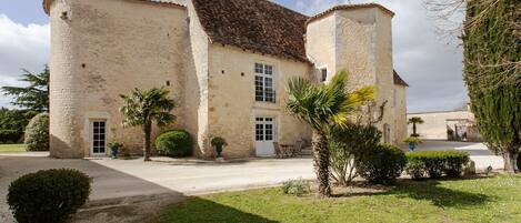 A stone building with a courtyard, a palm tree, and a small garden.