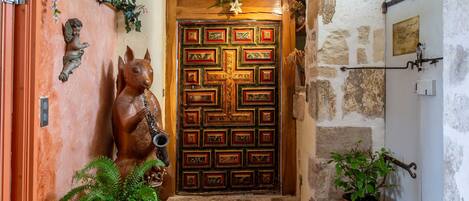 A wooden door with a decorative pattern, a small statue of a dog, and a potted plant beside the door.